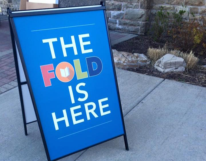 Sidewalk sign reading "The FOLD is here," advertising the Festival of Literary Diversity