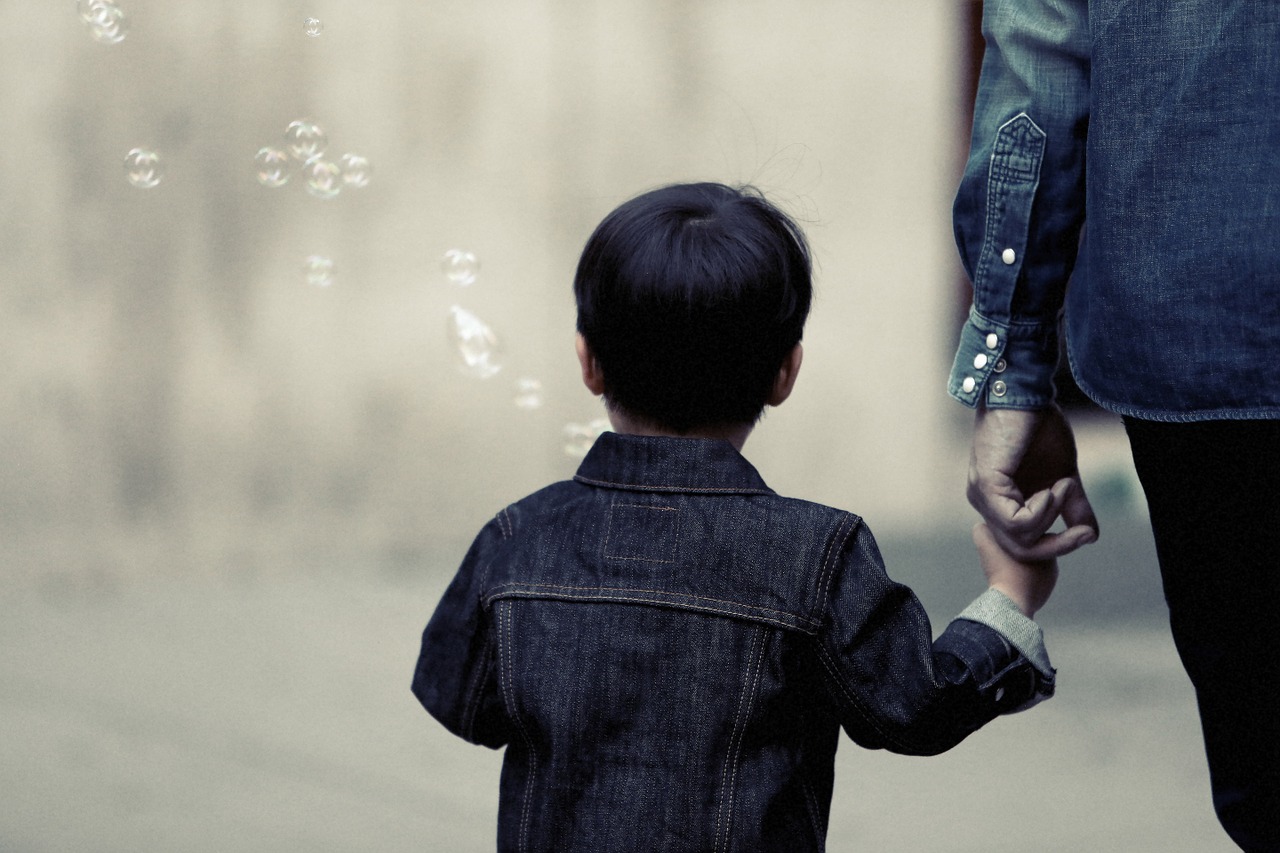 Little boy blowing bubbles, holding his mother's hand
