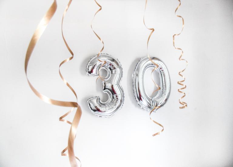 Silver balloons spelling out "30" and gold streamers