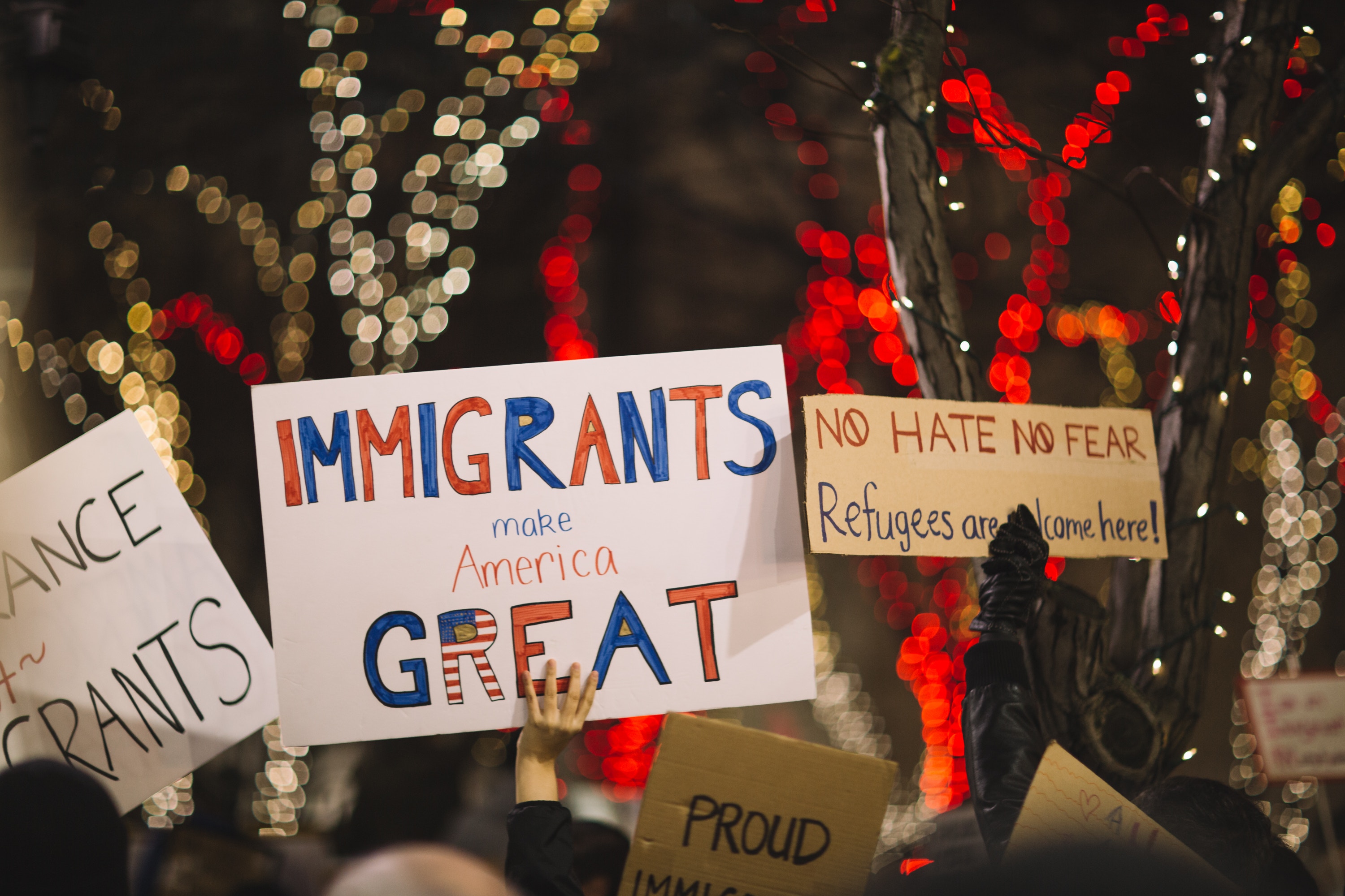 People at a march holding signs that say "immigrants make American great" and "no hate no fear"