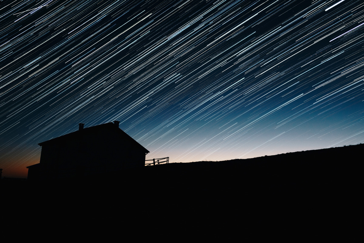 star trails over a house at night