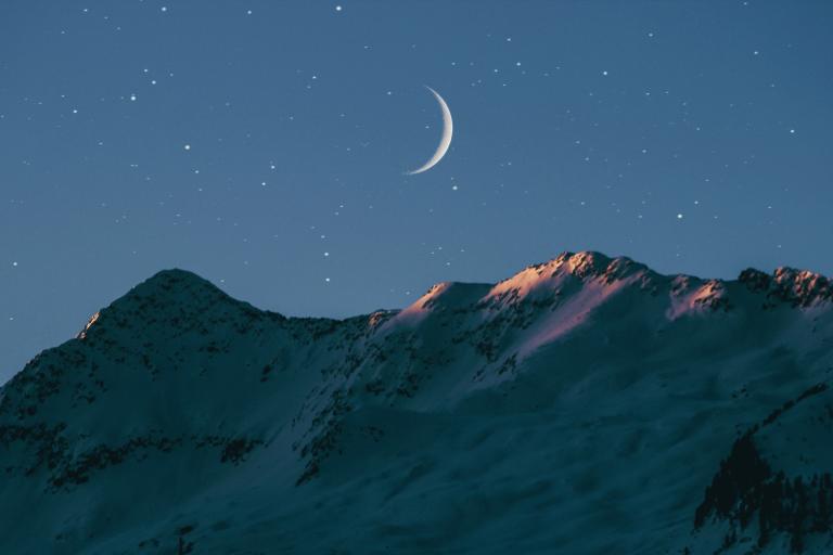 Crescent moon over mountain range