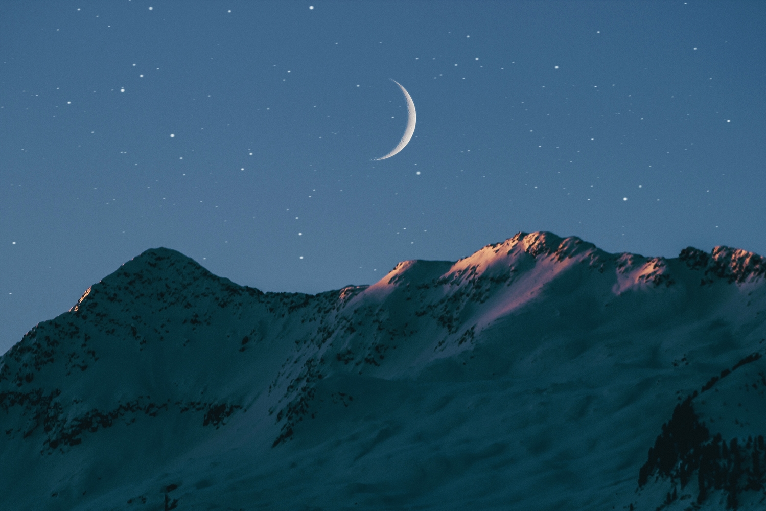 Crescent moon over mountain range