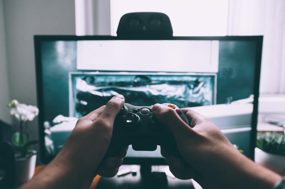 Hands playing video games in front of a screen