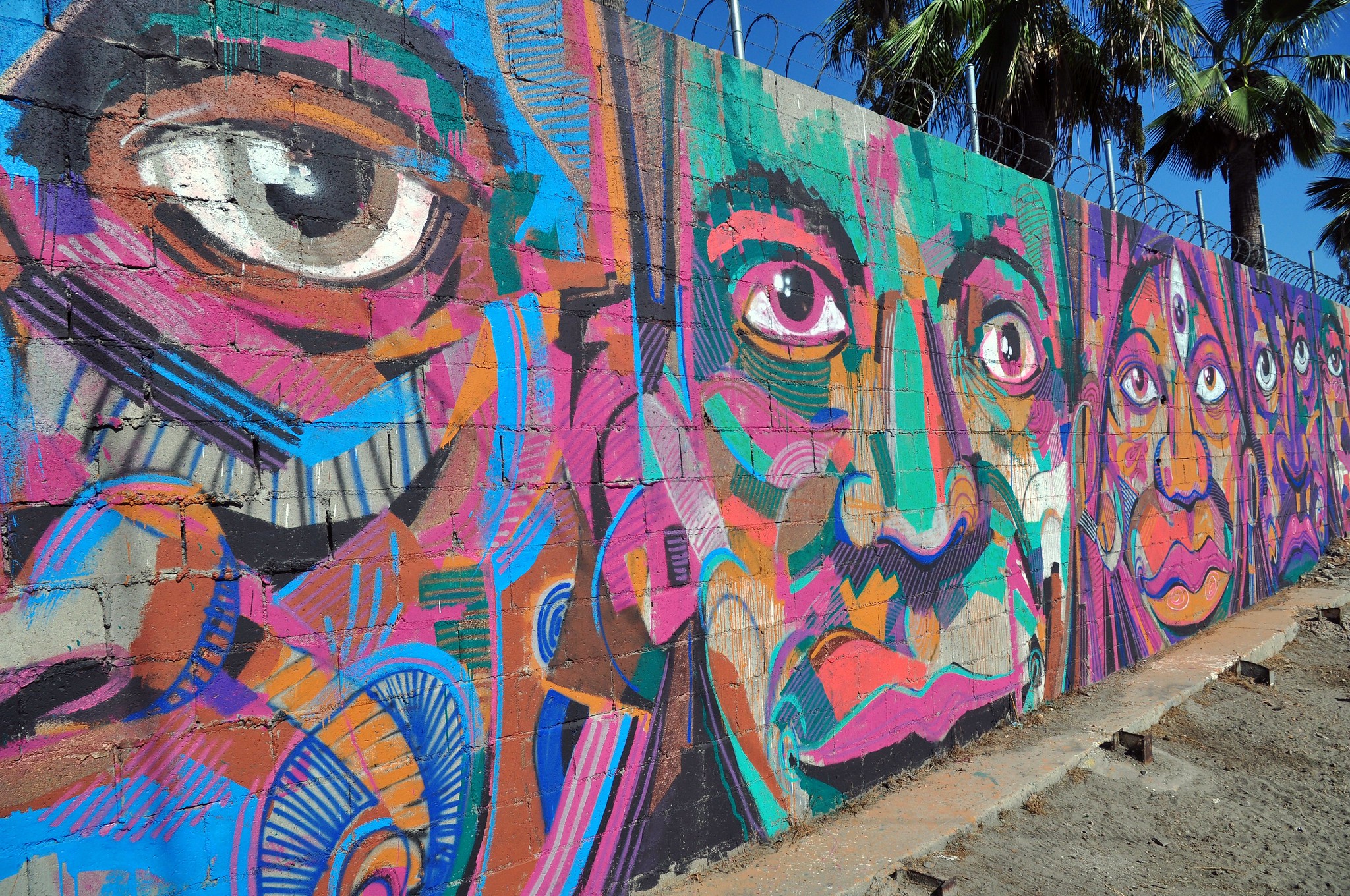 Faces painted on the US/Mexico border wall