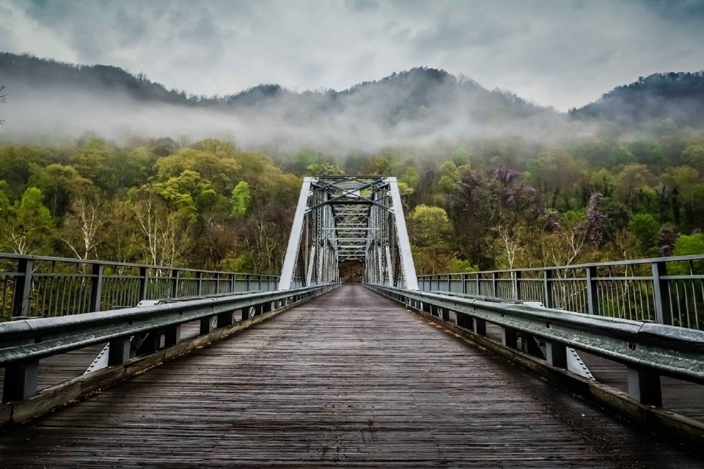 Wooden bridge heading into misty mountains