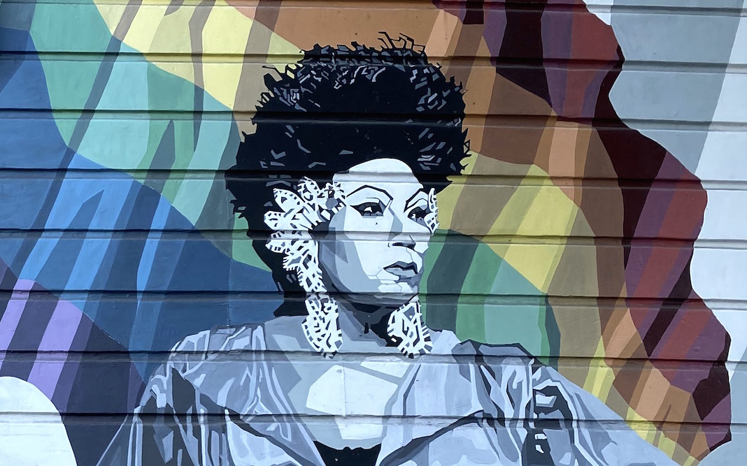 Mural showing Black woman standing in front of rainbow flag