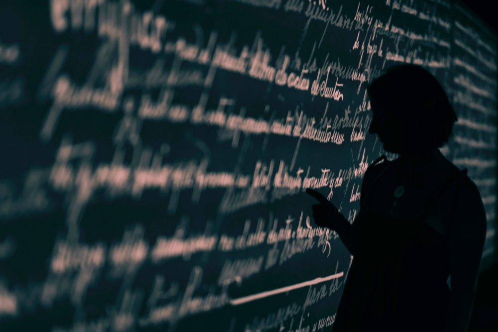 Silhouette of a person looking at words on a blackboard