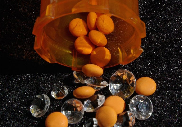 Pill bottle with pills and diamonds spilling out