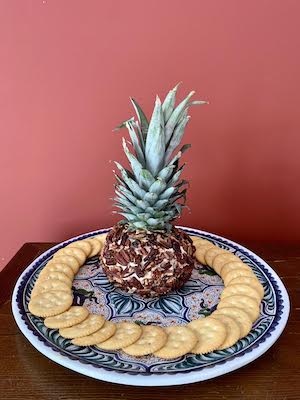 Cheese ball in the shape of a pineapple surrounded by crackers