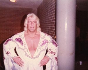 Vintage-looking photograph of Ric Flair in an ornately embroidered white costume with a plunging neck