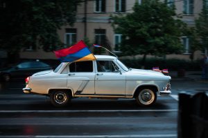 Car flying Armenian flag (red, blue, and gold stripes)