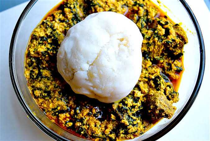 Stew of finely chopped vegetables and meat with a ball of pounded yam on top