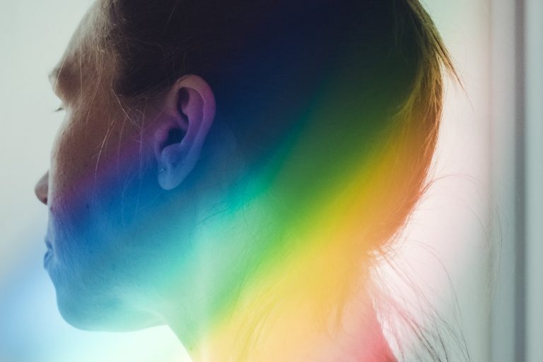 Person looking away from camera with a rainbow beside their head