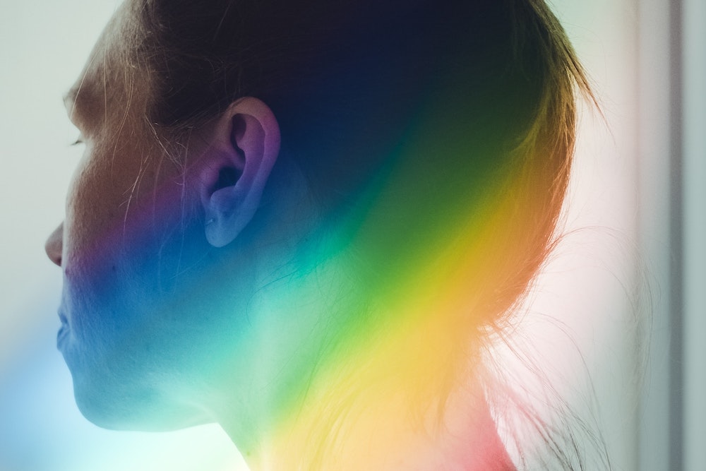Person looking away from camera with a rainbow beside their head
