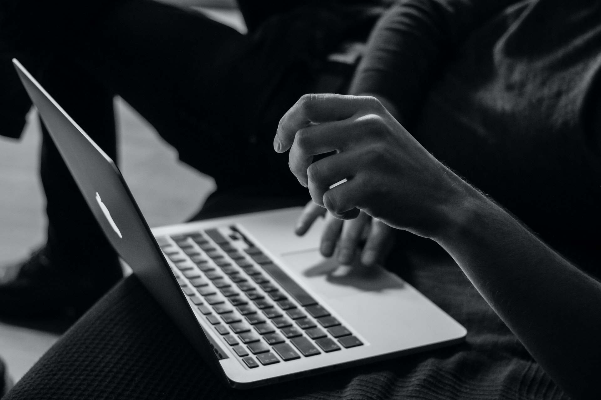 Black and white photo of hands using a laptop