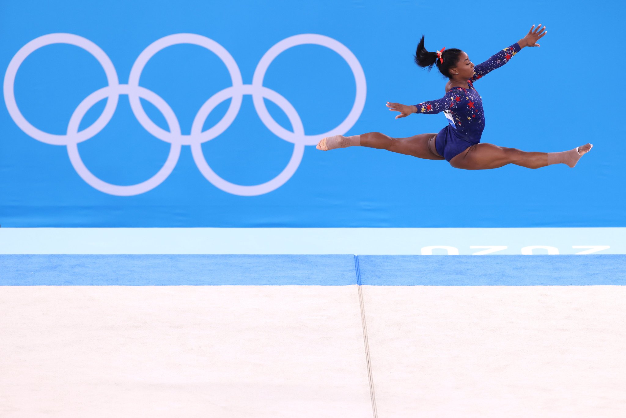 Simone Biles mid air in a split during her gymnastics routine at the 2020 Summer Olympics.