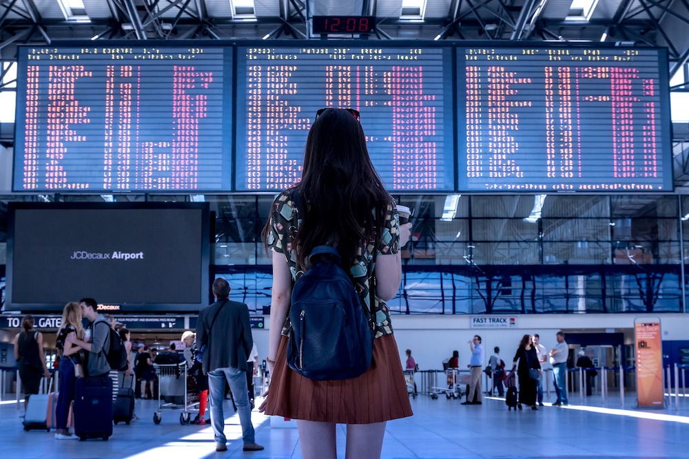 Woman looks up at airport departures sign
