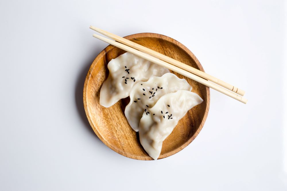 Three white dim sum in a wooden bowl