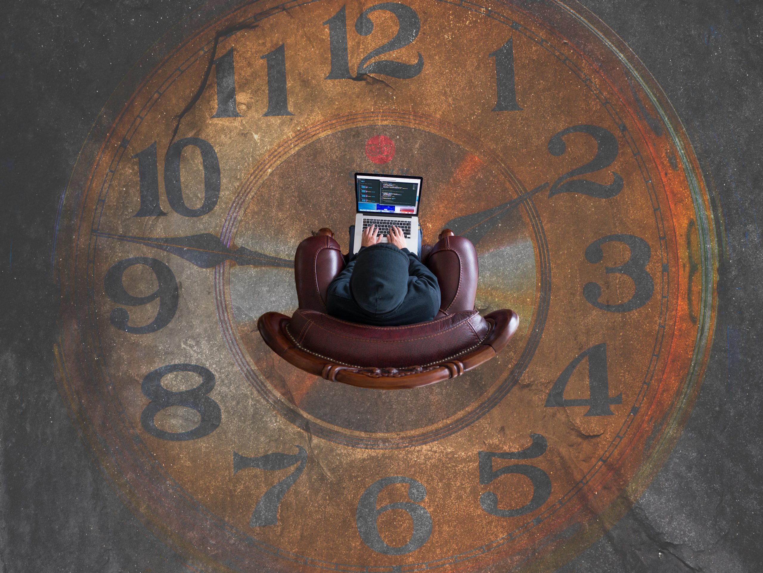 Person working on their laptop over a clock painted on the floor.