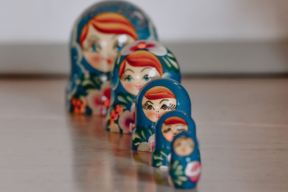 Five blue nesting dolls sit on a table in descending order.