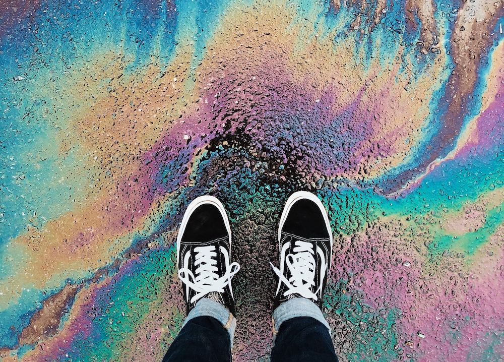A person wearing vans standing on top of post-rain oil sheen.