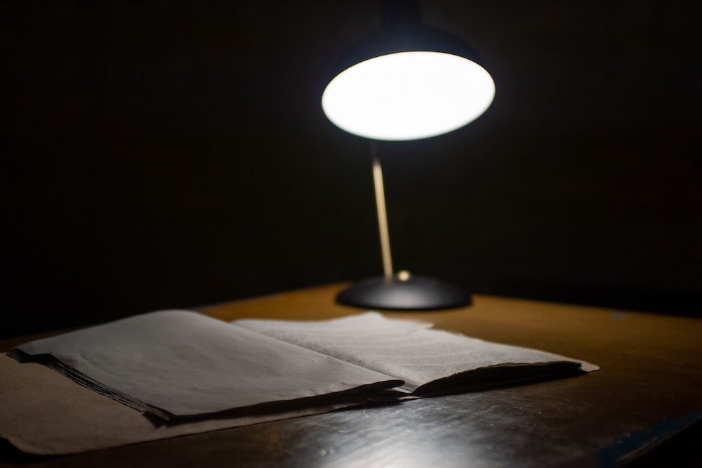 Lamp shining upon a desk in the darkness