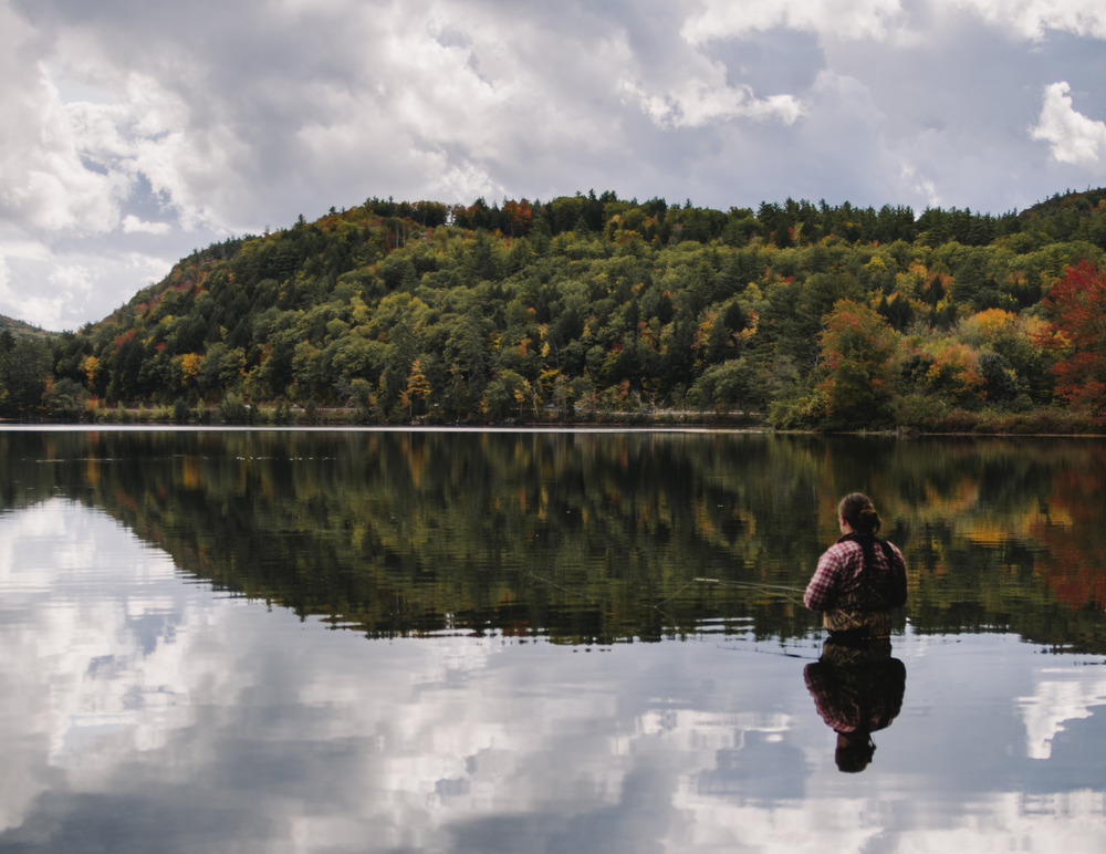 A person fishes waist-deep in a lake