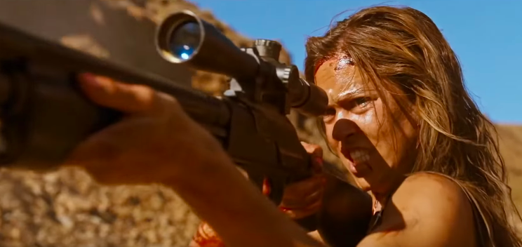 A woman stands in the desert and points a gun at someone off-screen