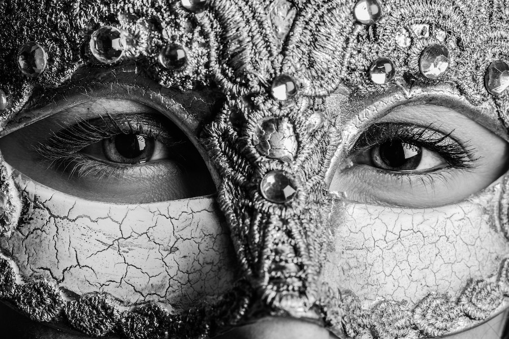 A woman peers out from behind a Mardi Gras mask