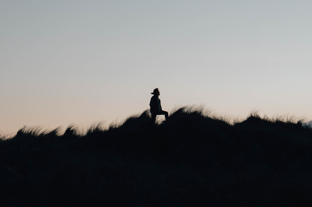 A person stands near a field on a beach