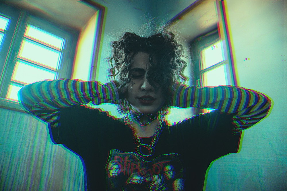 A woman in blue and black striped long sleeve shirt holds her hands over her ears