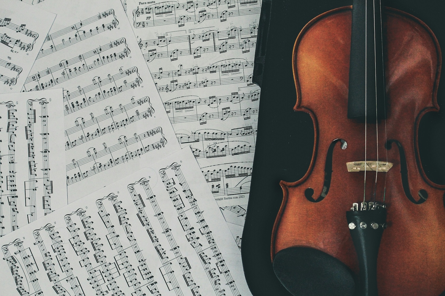 A stock image of a violin surrounded by sheet music.