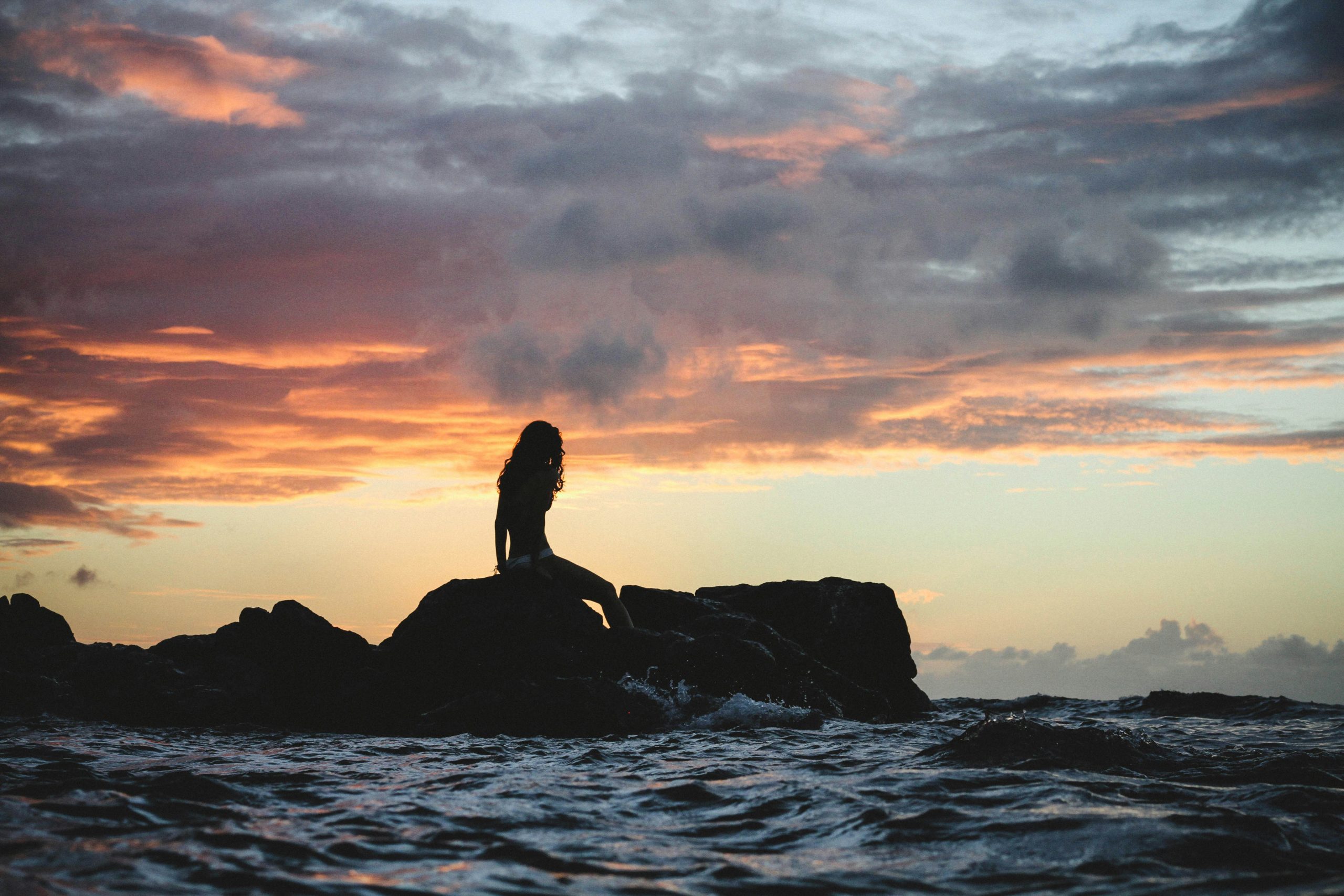 Woman on rock looking out over the ocean
