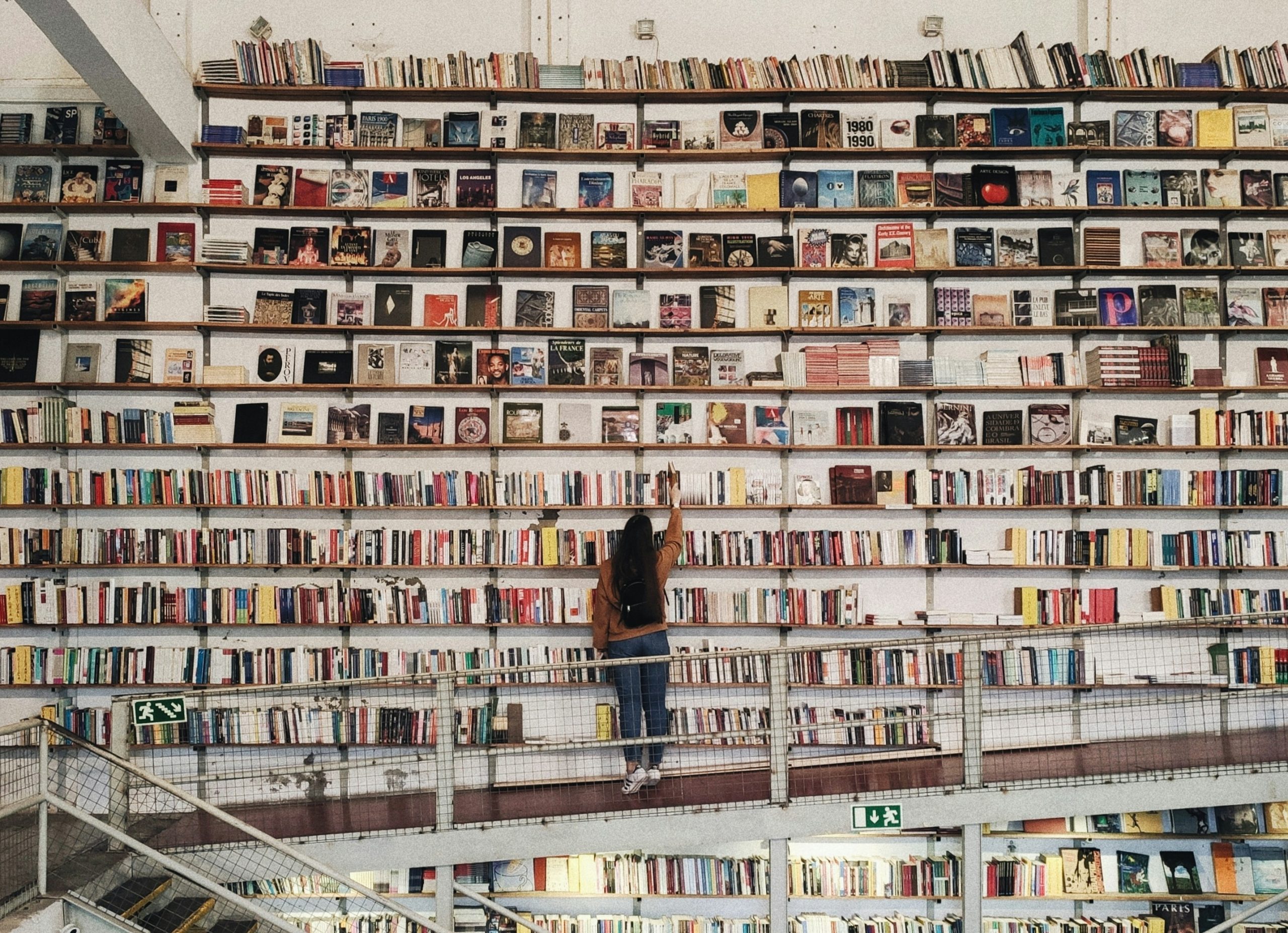 Woman standing in front of wide shelves of books