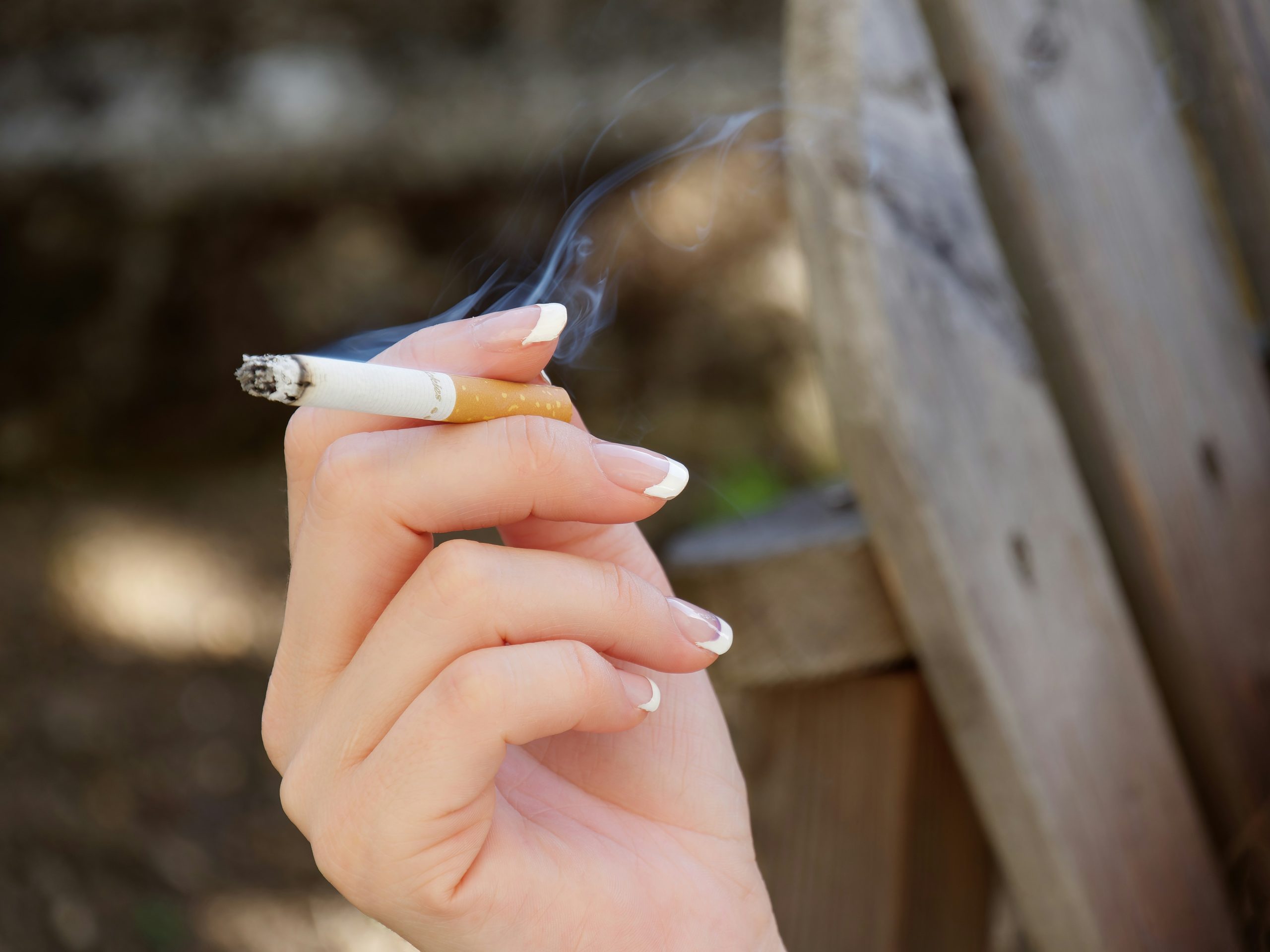 Hand holding a cigarette in an outdoor background
