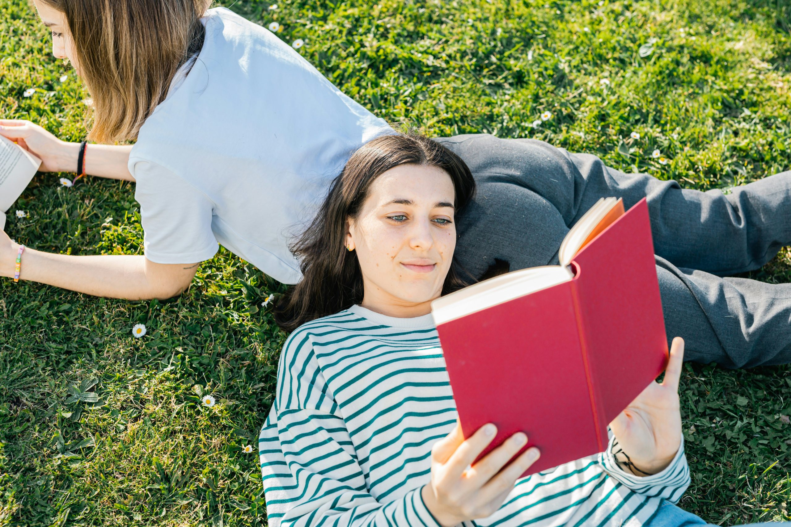 woman lying on the grass reading a book