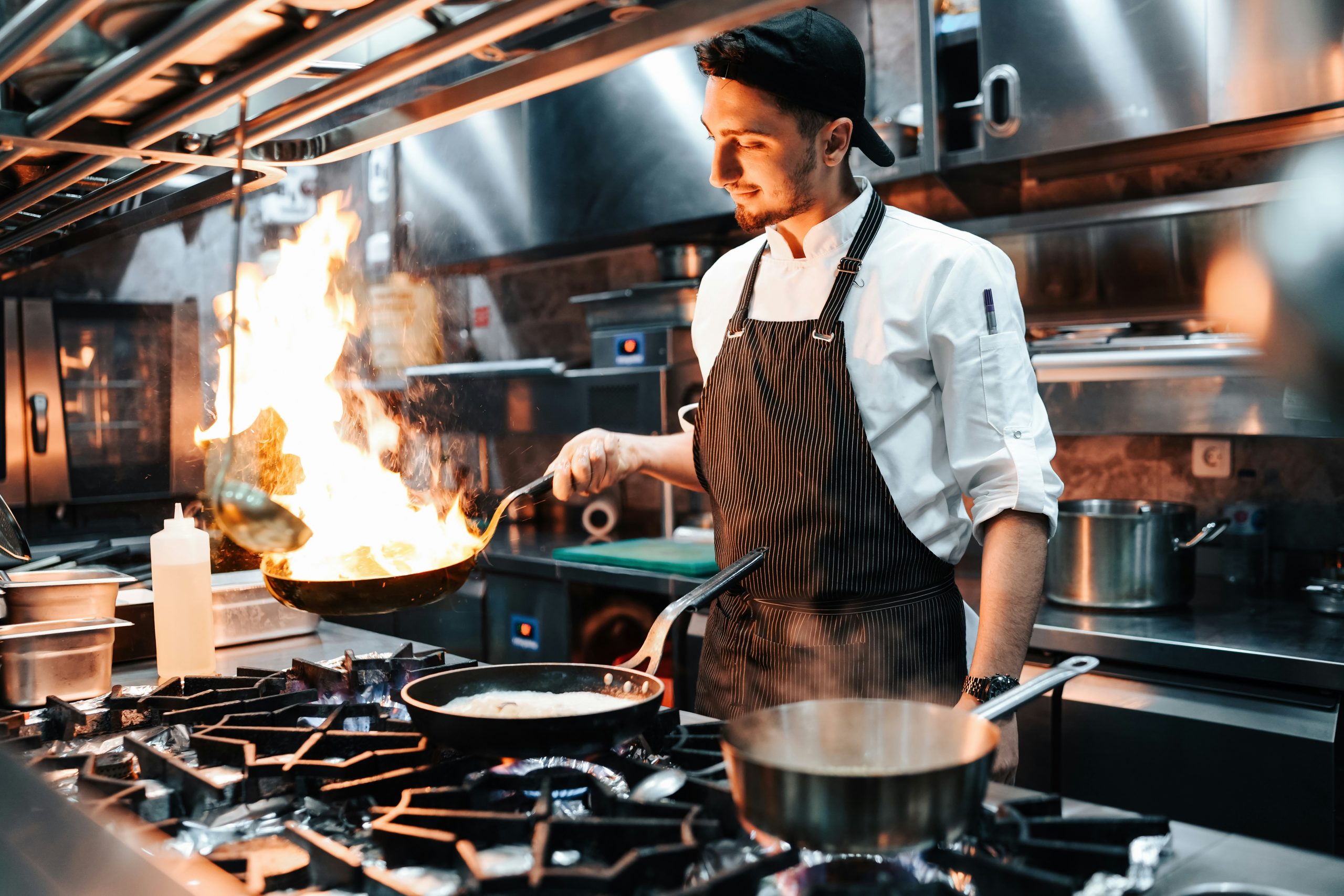 Chef in kitchen with pan on fire