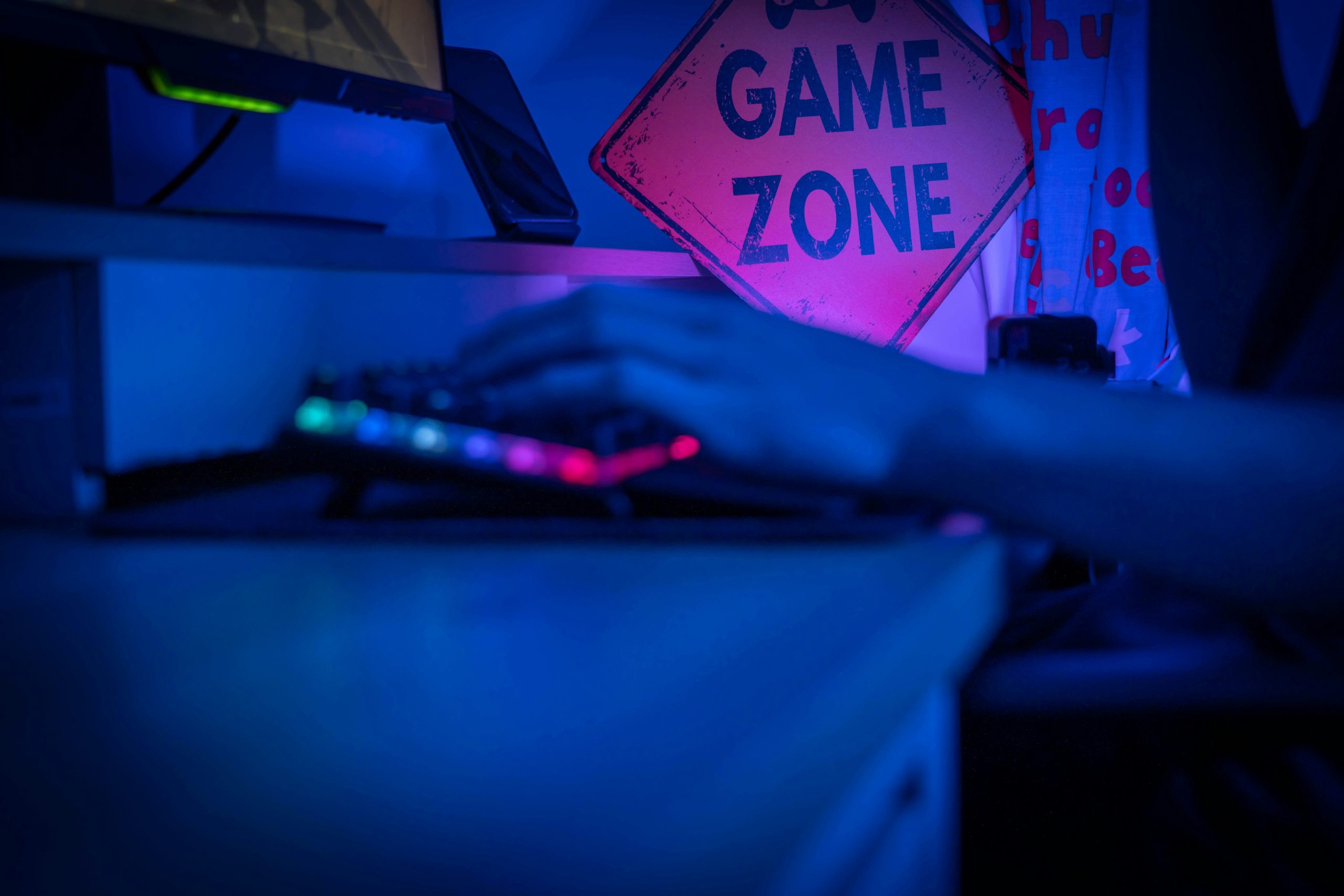 Person typing on keyboard in front of "Game Zone" sign