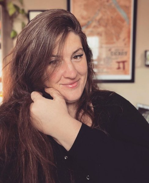 Author, Elizabeth Austin, in black clothes and long hair, smiling into the camera