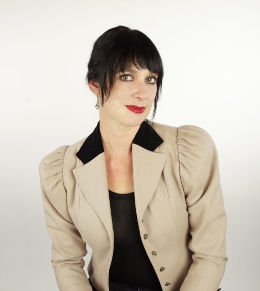 Author Summer J Hart in a beige top and dark hair looking into the camera.