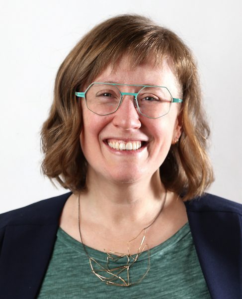 Author, Ali Moss, with chin-length hair and specs, smiling into the camera.